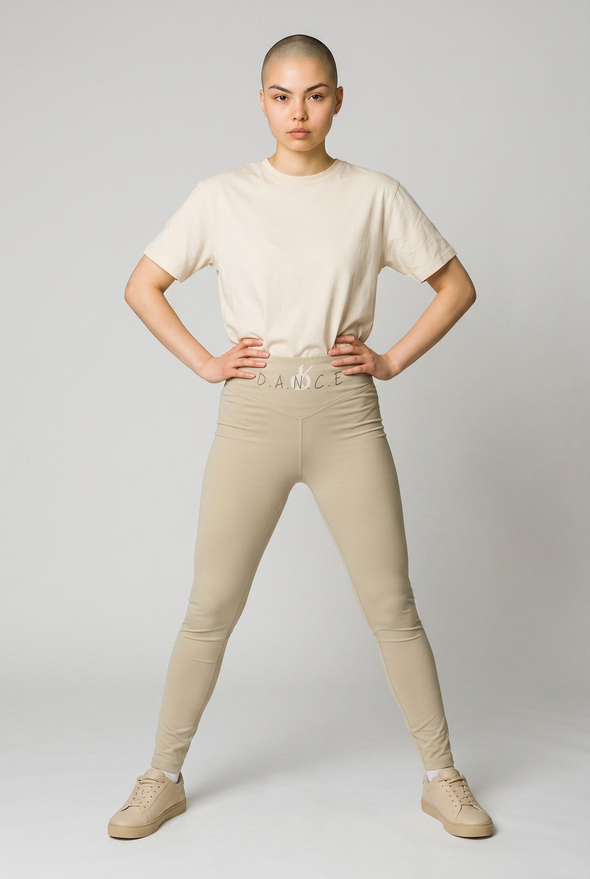 MONROE STORE high-waisted beige yoga leggings with a V-shaped waistband and subtle 'D.A.N.C.E.' logo detail.