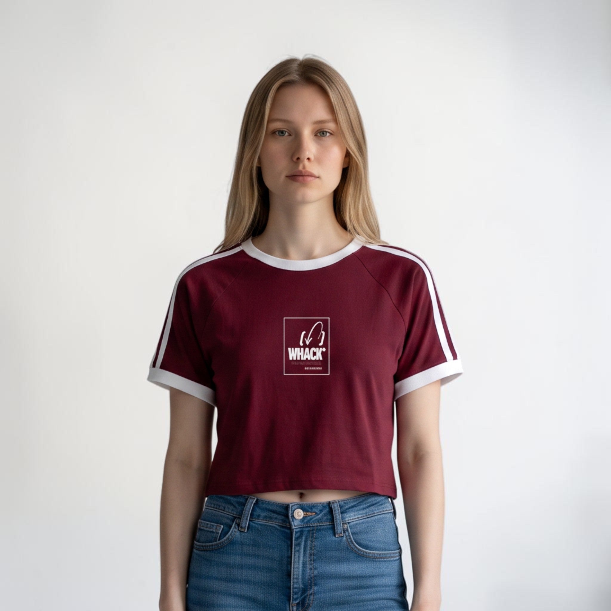 Modelo vistiendo camiseta crop raglan color granate con detalles blancos de MONROE STORE y jeans azules.