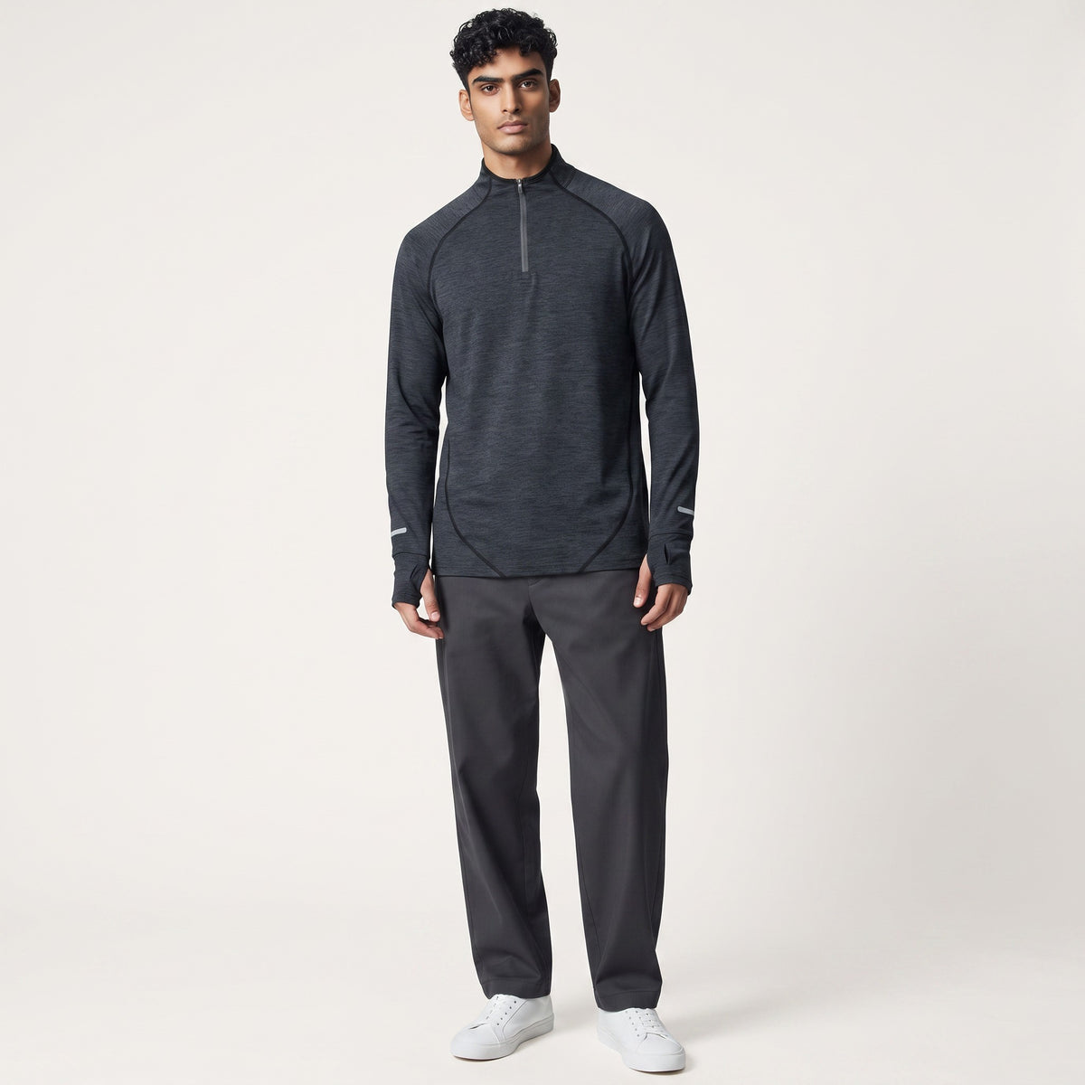 Modelo masculino vistiendo camiseta deportiva gris de manga larga con cremallera de MONROE STORE y pantalones oscuros.