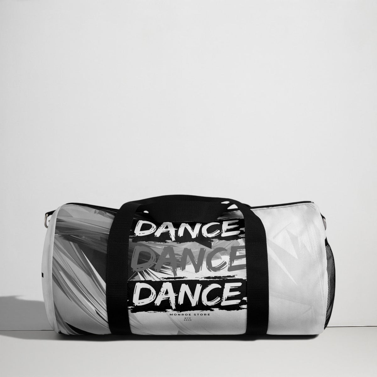 MONROE STORE duffel bag with "DANCE" repeated in black and white graphic print, black handles and mesh side pocket.