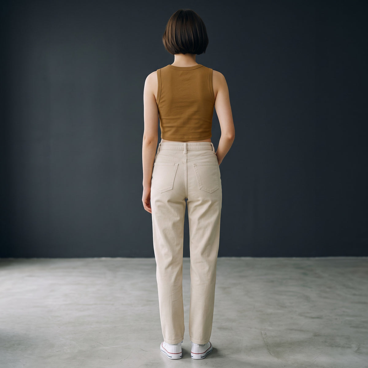 Mujer de espaldas vistiendo top corto marrón de cuello redondo MONROE STORE con pantalones beige